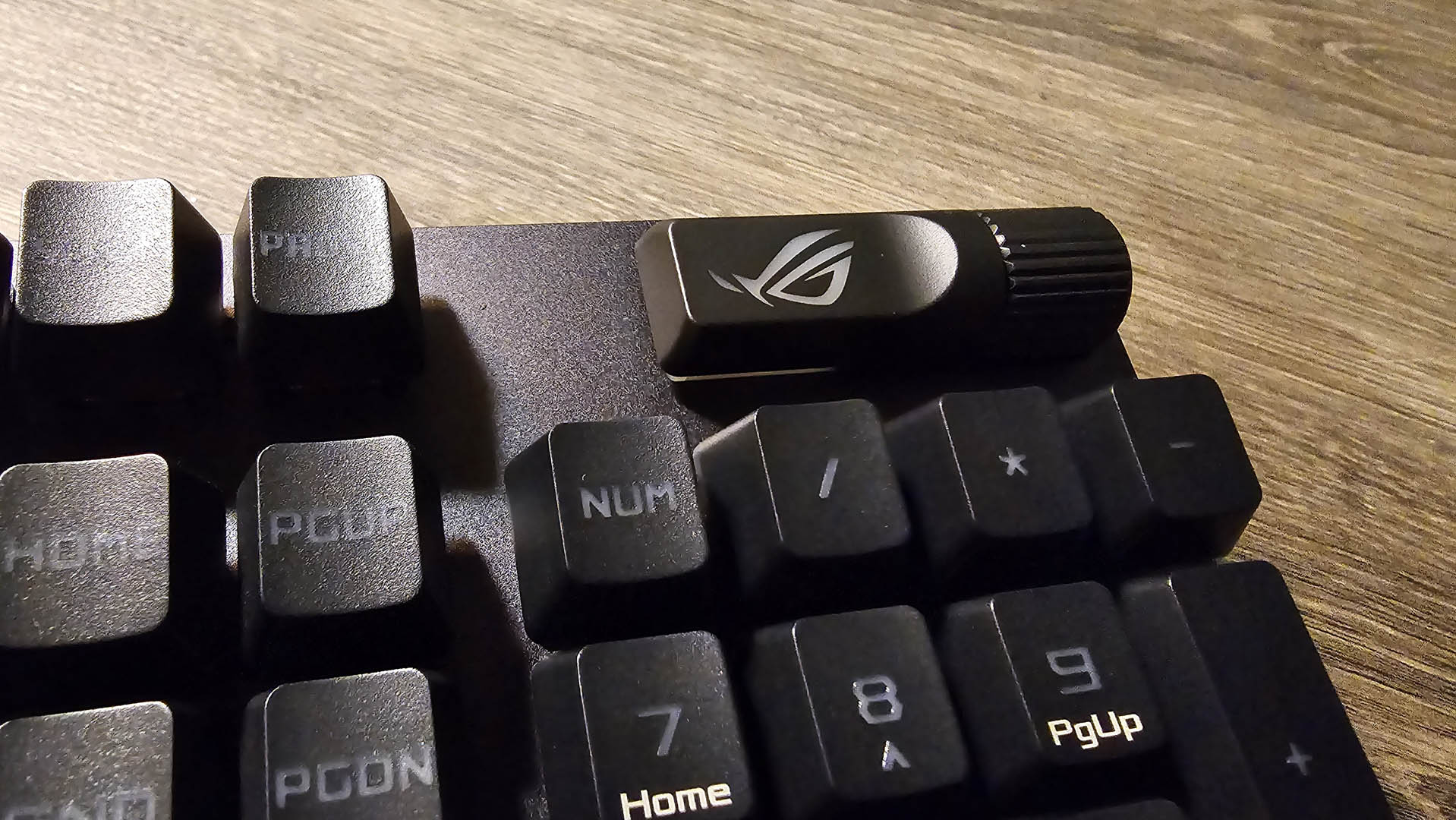 The Asus ROG Strix Scope II RX gaming keyboard photographed on a wooden desk.