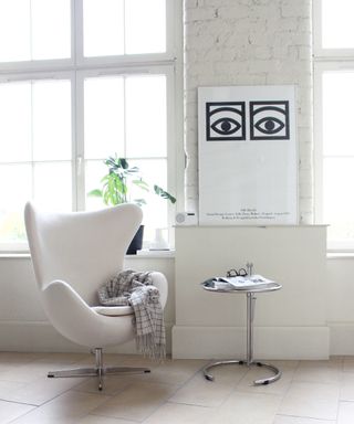 white armchair in white room with table and artwork