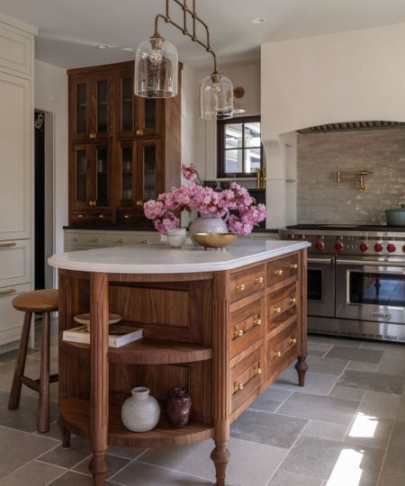 An arts and crafts kitchen with a wooden freestanding island with turned legs and ogee countertop edges
