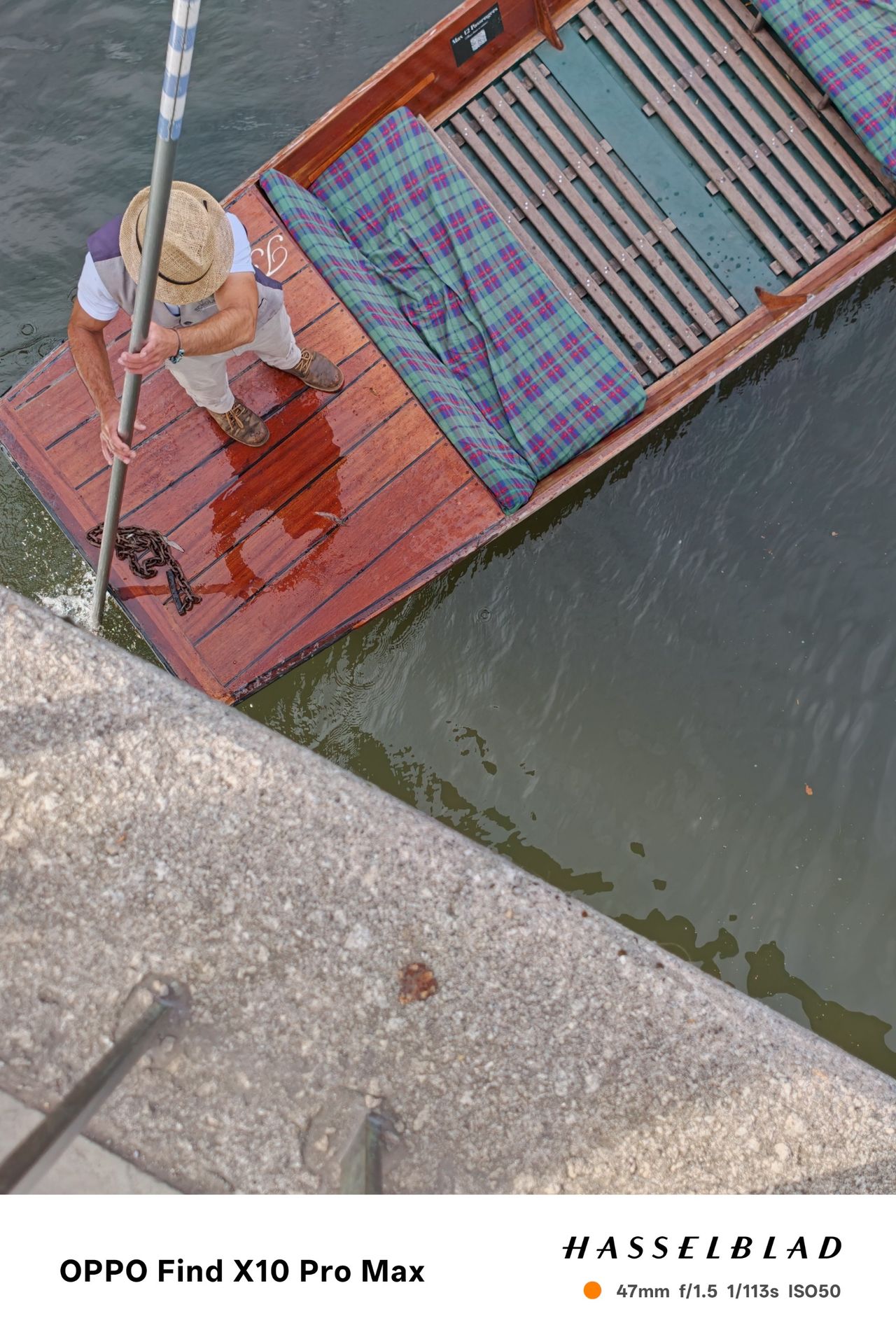 Punter steering a wooden boat viewed from a bridge above the river.