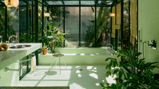 A bathroom designed with green floor and wall tiles, with glass ceiling and windows