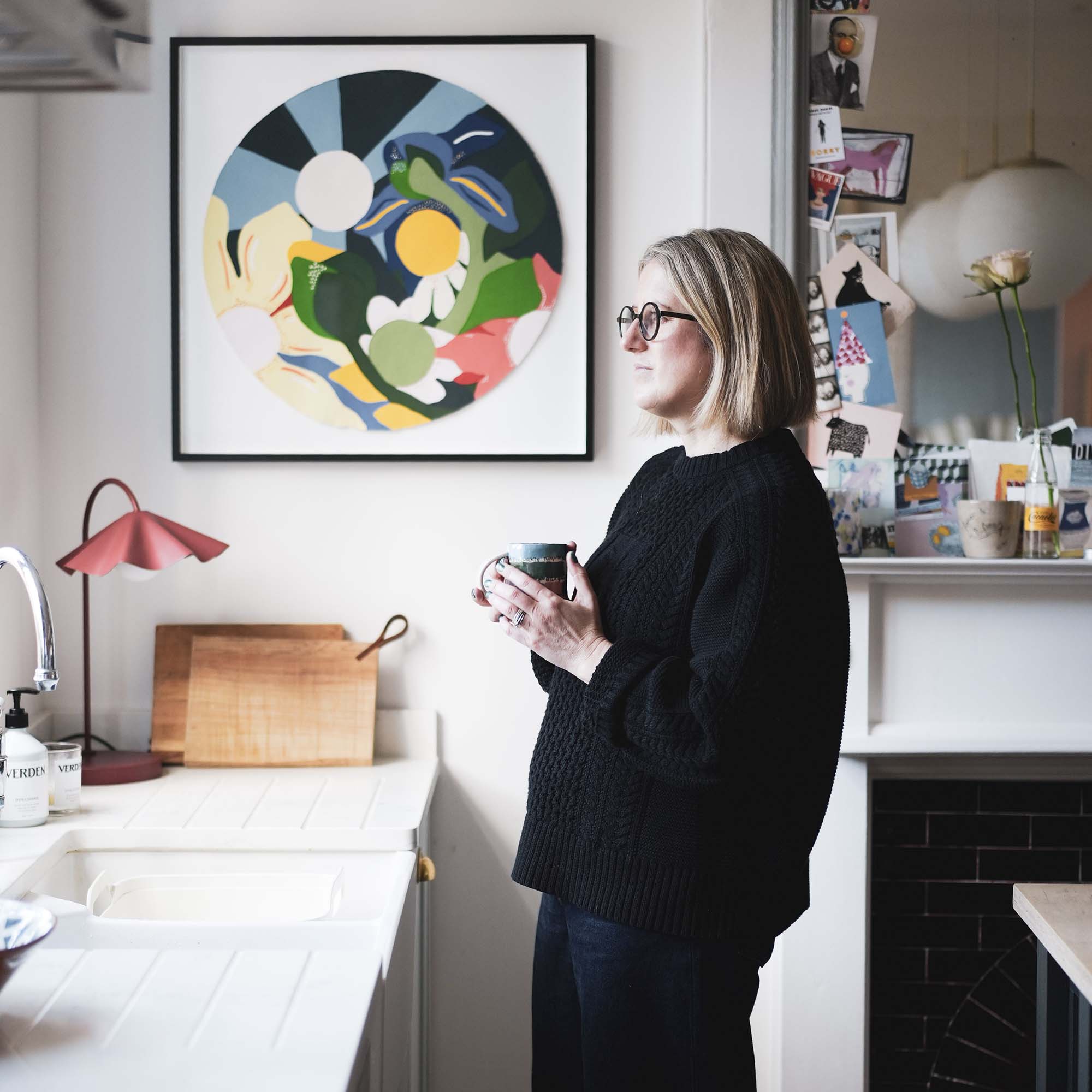 woman standing up in a kitchen next to some graphic framed art