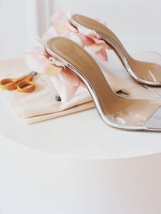 a pair of pvc heels with floral details in front of a plain backdrop