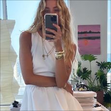 Olympia Gayot posing in front of mirror with white tank and white skirt 