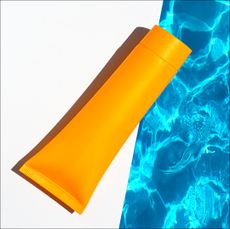 orange tube of sunscreen next to a pool