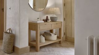 small hallway with oak console table, wooden floor, mirror above table and plaster effect walls