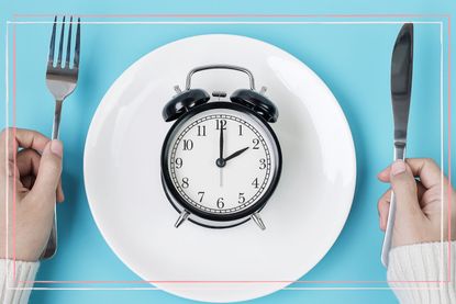 An alarm clock on a plate with a knife and fork held either side