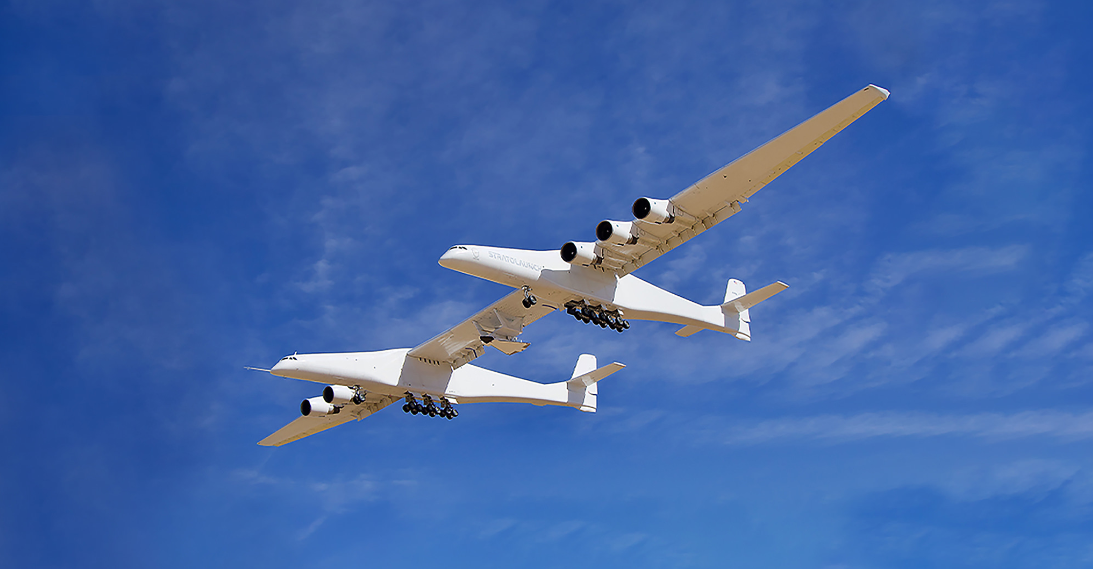 uma aeronave branca dupla fuselagem com um avião de foguete experimental sob sua asa