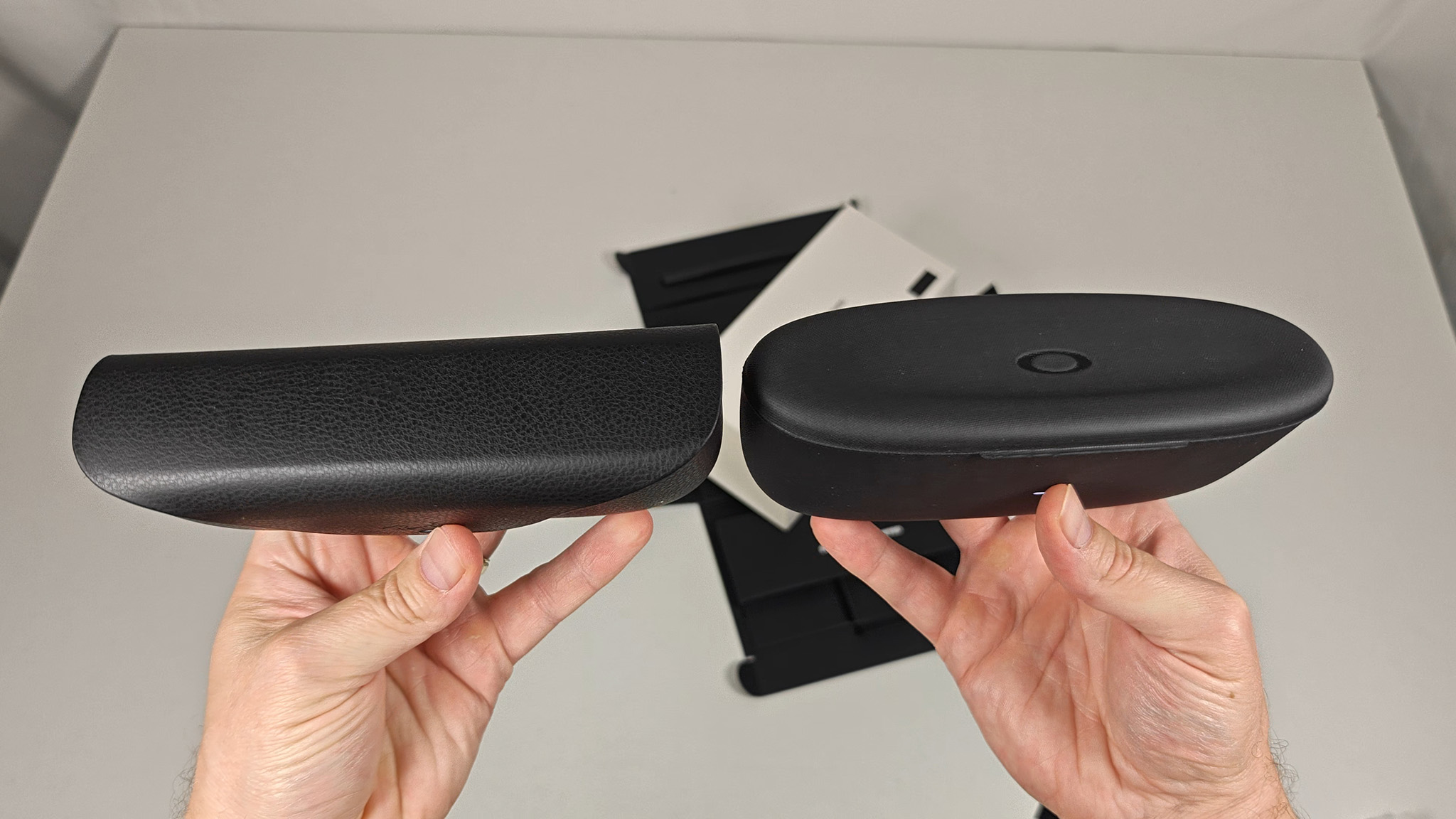 Comparing the size and shape of Ray-Ban Meta Smart Glasses and Oakley Meta HSTN's charging cases