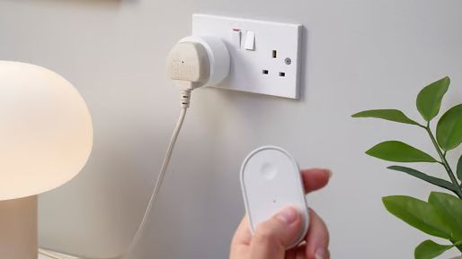 A hand using a remote in front an IKEA smart plug
