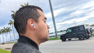 Man wearing AirPods Pro 2 outside with the sky and palm trees in the background