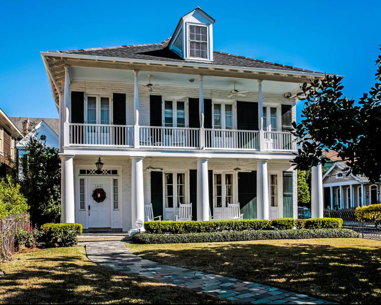 Exterior of white brick French colonial style house with balconies and columns