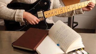Close-up of a woman playing a Squier Telecaster Deluxe with a book of notes