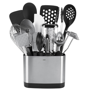 Black and chrome 15 piece kitchen utensil set, which includes spoons, spatulas, a grater, tin opener and tongs stored in a chrome utensil pot.