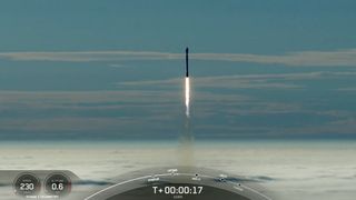 a black-and-white spacex falcon 9 rocket launches into a blue sky, rising above a blanket of fog