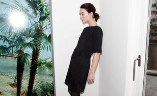 Model in black dress leaning against wall