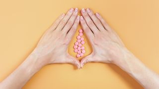 hands in shape of vagina with pink pills