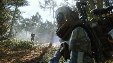 A soldier hides in a forest as an enemy approaches in the distance