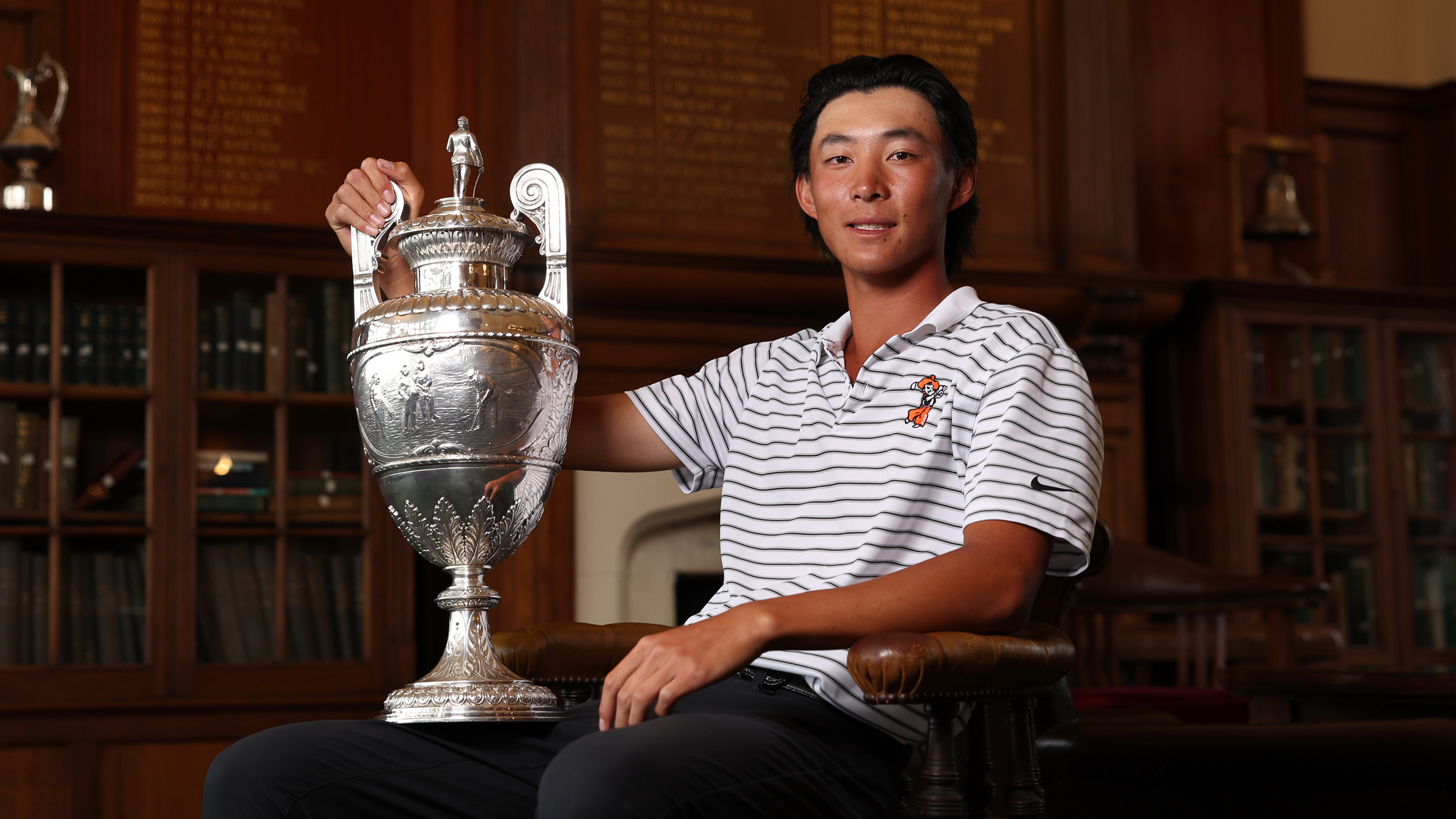 Ethan Fang poses with The Amateur Championship trophy on his knee after winning in 2025