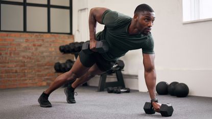 Black man, dumbbell row and training in gym, workout and strong fitness in health club. Serious sports athlete, bodybuilder and weight exercise on ground for energy, power and core strength challenge