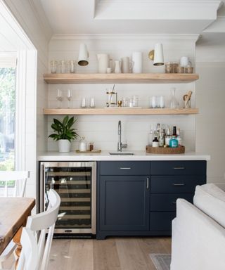 Home bar with lower cabinetry painted in Benjamin Moore Hale Navy paired with a ceaserstone countertop and open shelving