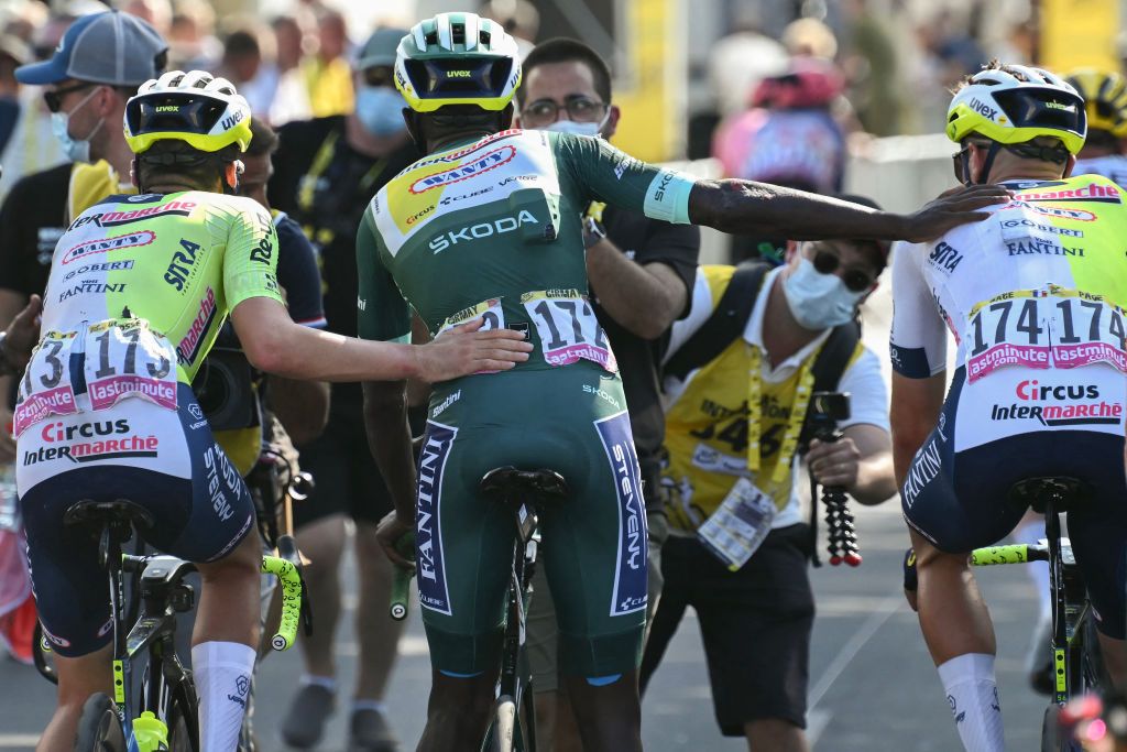 Intermarche - Wanty team's Eritrean rider Biniam Girmay wearing the sprinter's green jersey is assisted by teammates as he cycles past the finish line after crashing in the final kilometers of the 16th stage of the 111th edition of the Tour de France cycling race, 188,6 km between Gruissan and Nimes, southern France, on July 16, 2024. (Photo by Marco BERTORELLO / AFP)