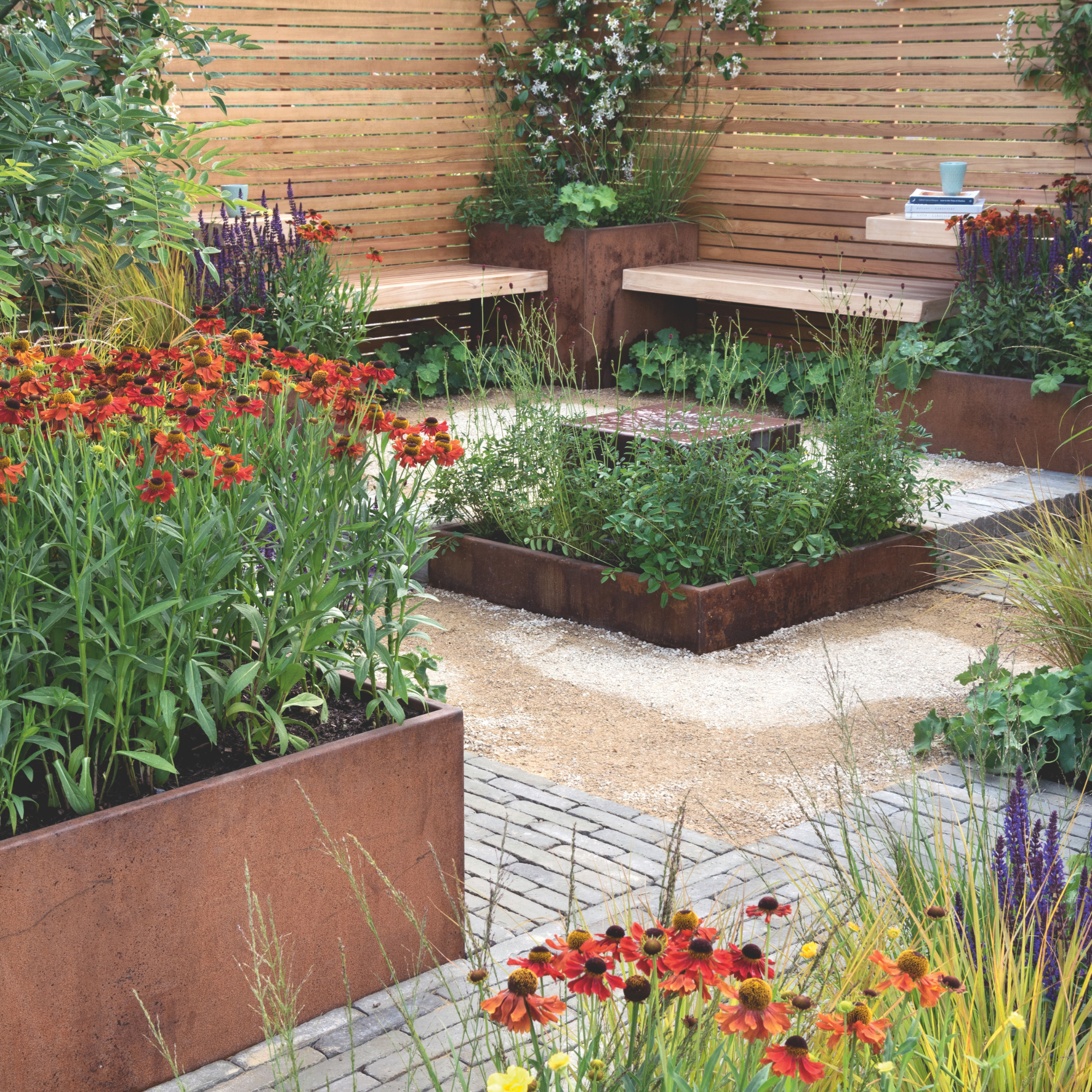 Corten steel raised planters in a garden seating area.