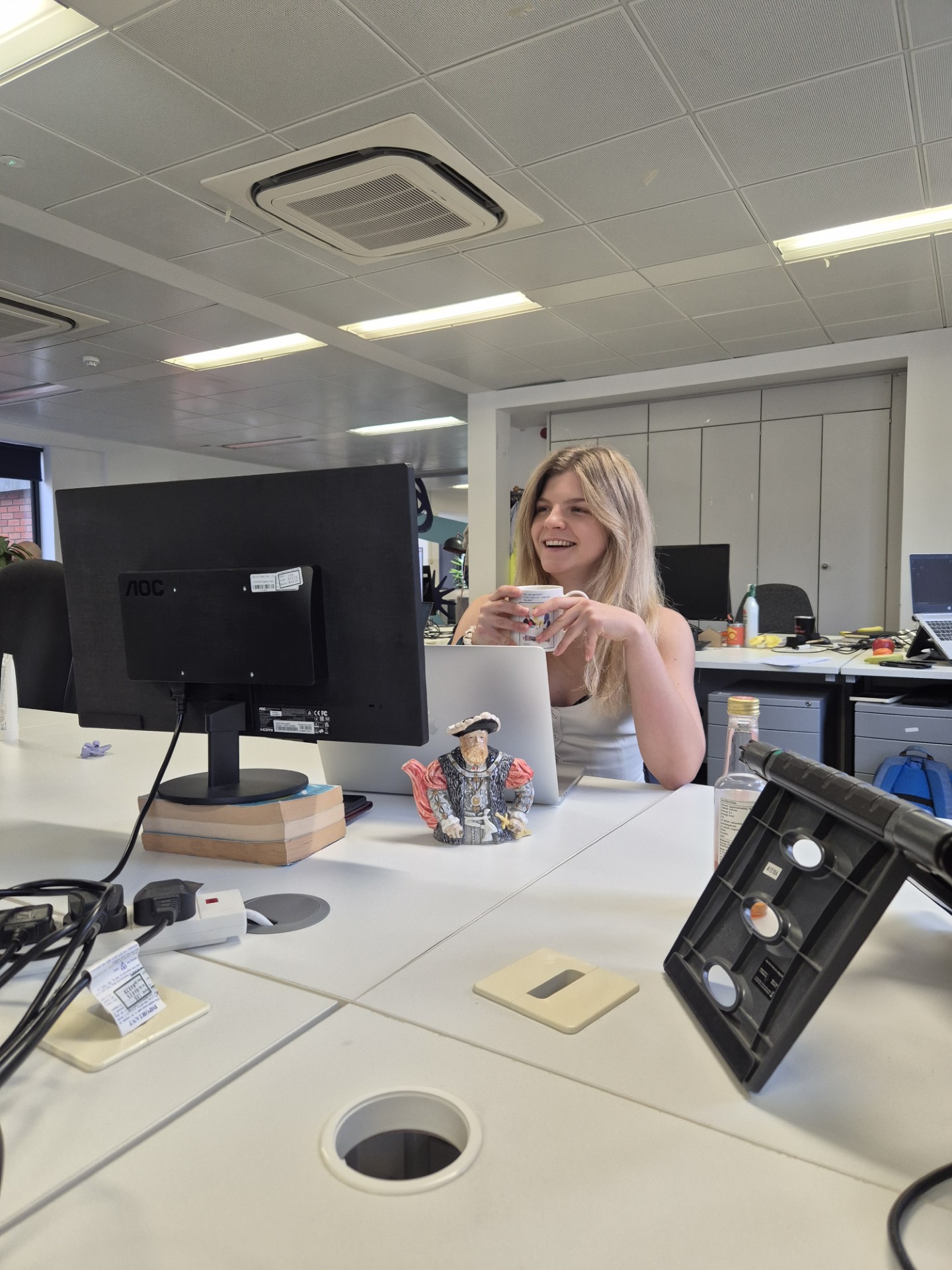 woman sitting at a desk holding a cup of something