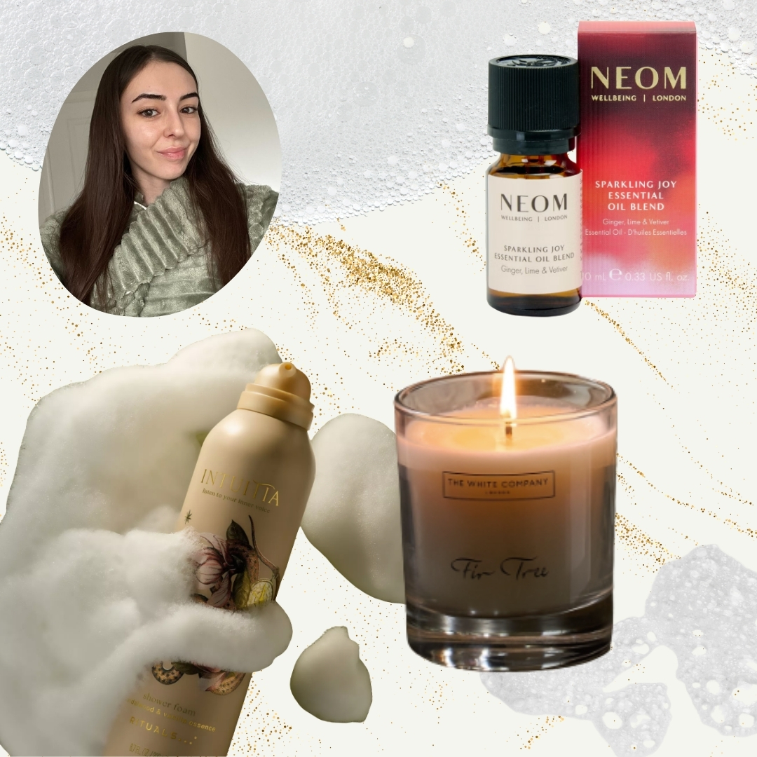 A picture of Digital Beauty Writer, Sennen Prickett, wearing a green dressing gown, alongside product pictures of the Rituals Limited Edition Intuitia Velvety Foaming Shower Gel, The White Company's Fir Tree Luxury Signature Candle and the NEOM Sparkling Joy Essential Oil Blend on a cream background with a gold glitter and bubble bath overlay