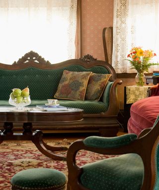 Victorian style living room with ornate green sofa, pale pink patterned sofa and floral carpet