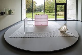 Exhibition vignette with pink chest of drawers on checkered rug by Wieki Somers