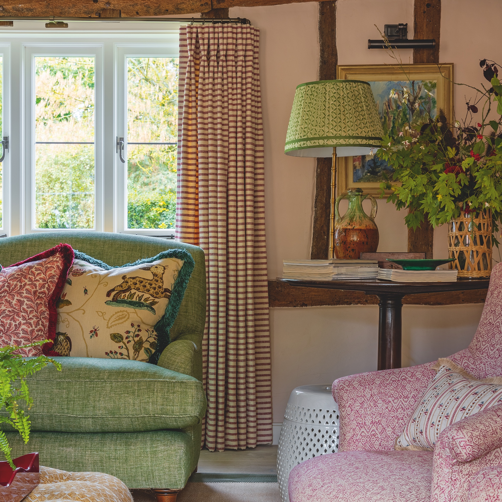 sitting room with green sofa and pink armchair with pink walls and stripe curtains