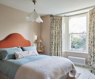 Summer pastel bedroom with red and blue bed and floral curtains