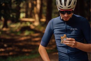 Male cyclist eating an energy bar on a bike ride to avoid bonking