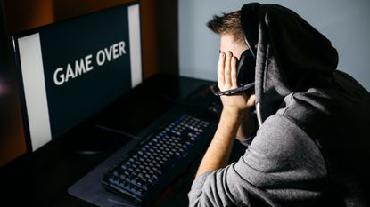 Gamer with head in hands looking at game over screen