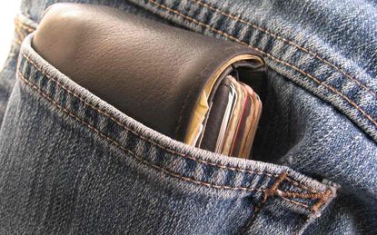 A wallet juts out of the back pocket of a pair of blue jeans