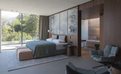 Bedroom in earth tones, with full-length sliding doors to balcony and door to en-suite bathroom