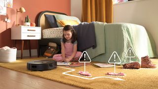 A Roomba j9+ navigating a child's room which has socks and boots strewn over it - and a girl drawing on the floor.