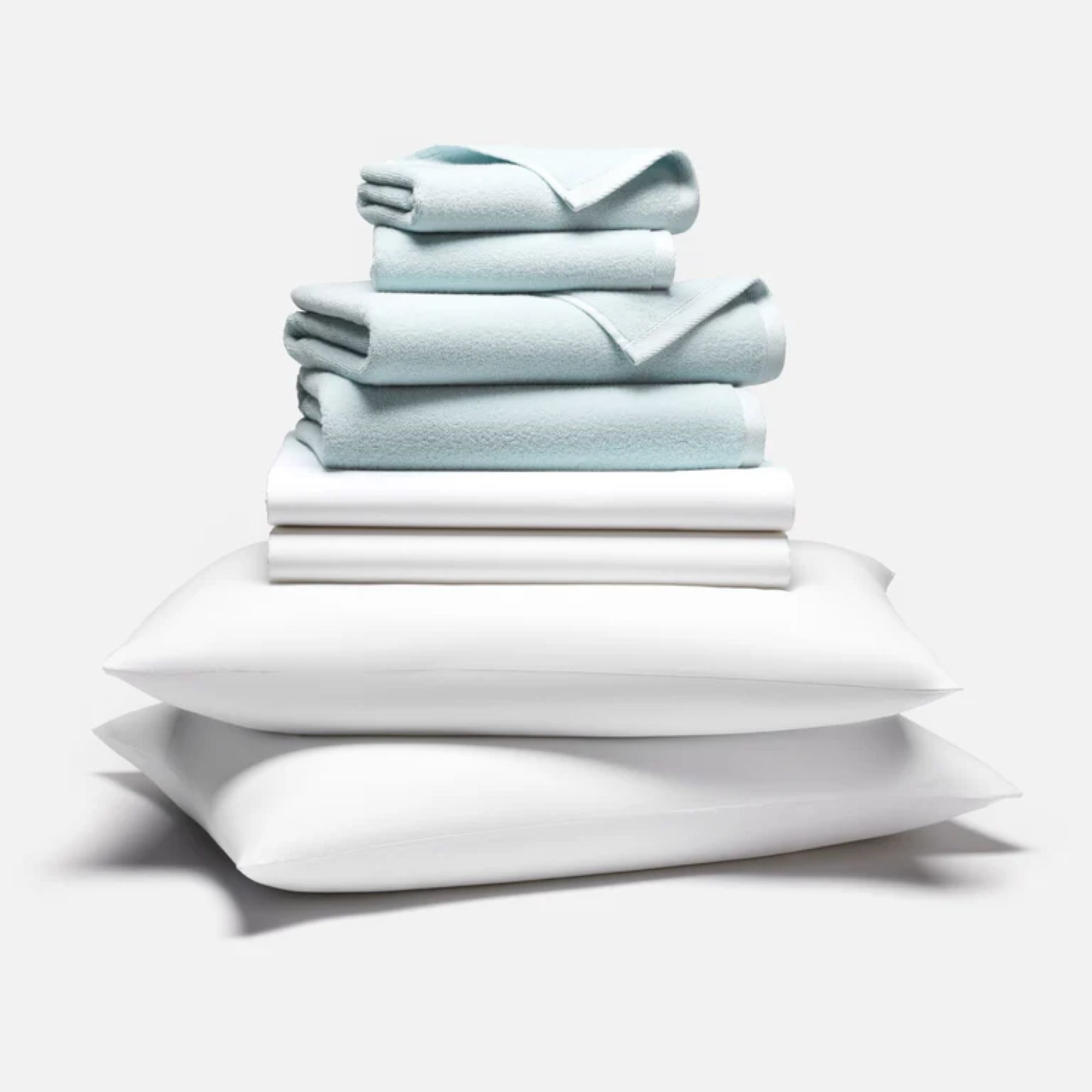 White pillow and sheet set with pale blue folded towels