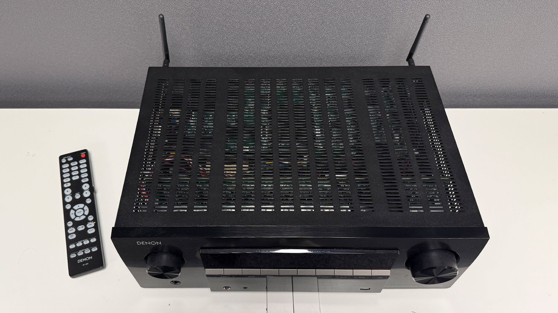 Denon AVR-X2900H home cinema amplifier on white surface with remote control next to it