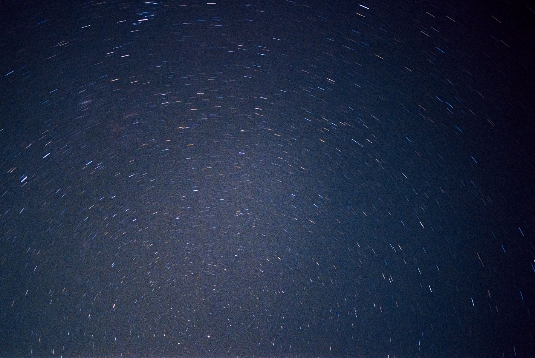 A visual of a photograph taken with a film camera that shows star trails instead of sharp points of light