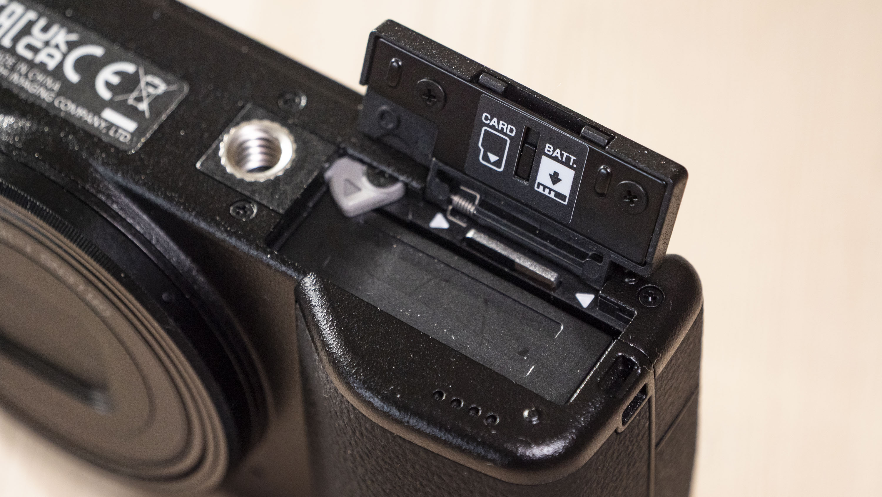 Closeup of the Ricoh GR IV compact camera's open battery door