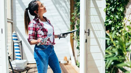 Woman painting outside of a house DIY