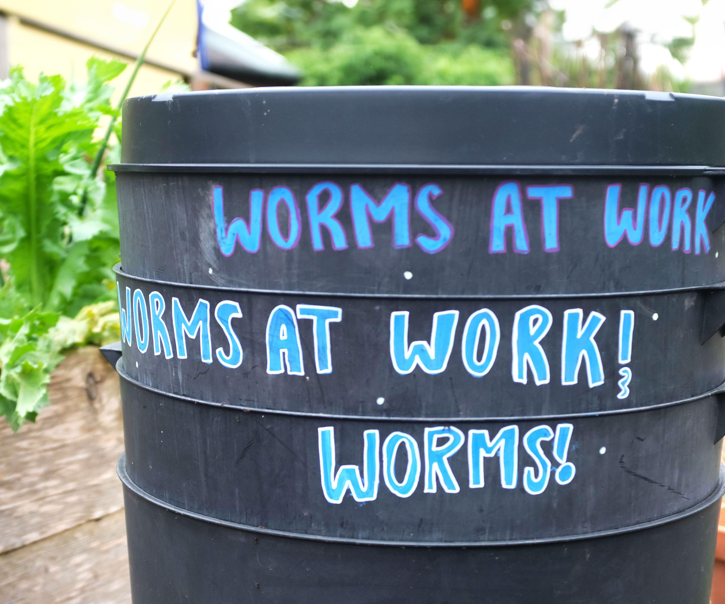 plastic worm composting tower in yard with blue lettering on side