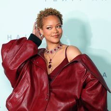 Rihanna wears an extra oversize leather jacket in front of a step and repeat for fenty hair