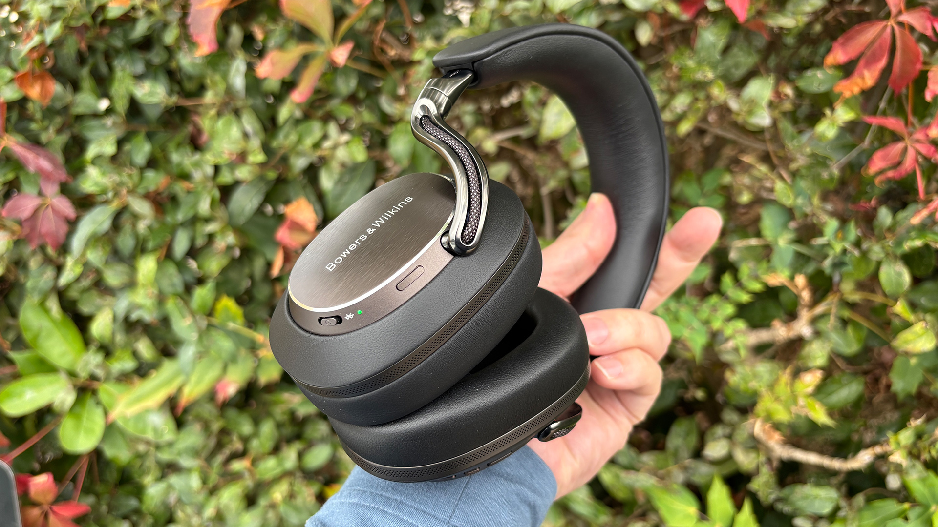 Bowers &amp;amp; Wilkins Px8 S2 wireless headphones held in hand in front of bush