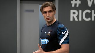 Phil Dunster as Jamie Tartt standing in the arena hallway in uniform while looking to the left in Season 3.