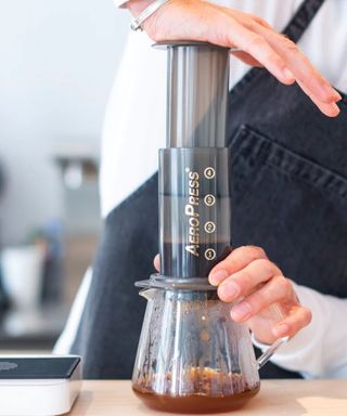 A barista demonstrating how to use a Aeropress coffee maker