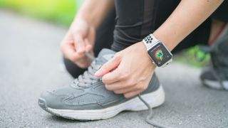 Woman wearing Apple Watch tying her running shoes