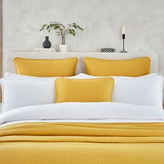 bedroom with bed white wall and yellow cushions